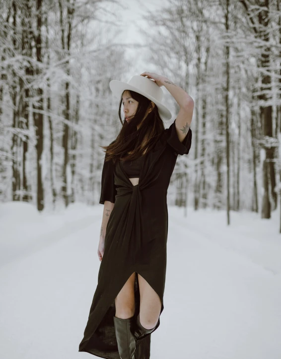 a woman in a black dress is standing in the snow, by Julia Pishtar, low quality photo, high quality image