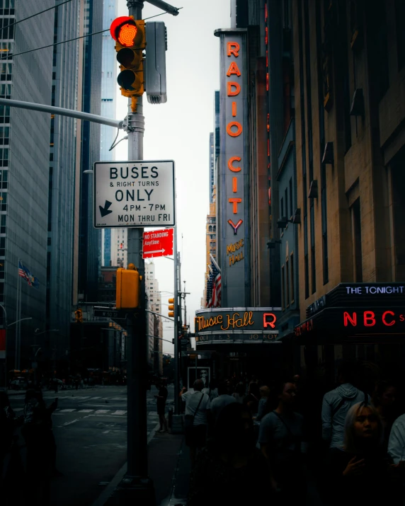 a group of people walking down a street next to tall buildings, a picture, pexels contest winner, harlem renaissance, signboards, background image, photo of a big theaterstage, post apocalyptic new york