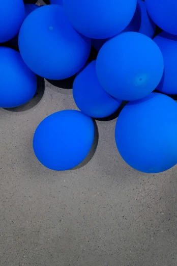 a pile of blue balloons sitting on top of a cement floor, inspired by Yves Klein, unsplash, kinetic art, spheres, softplay, 3/4 view from below, fluorescent spots