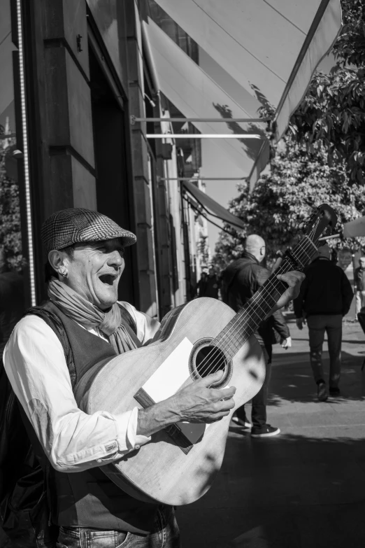 a black and white photo of a man with a guitar, inspired by Louis Stettner, pexels contest winner, laughing and joking, selling his wares, in barcelona, playful peasant man