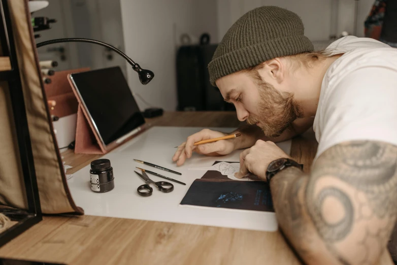 a man sitting at a desk writing on a piece of paper, an airbrush painting, by Adam Marczyński, trending on pexels, tattoo, avatar image