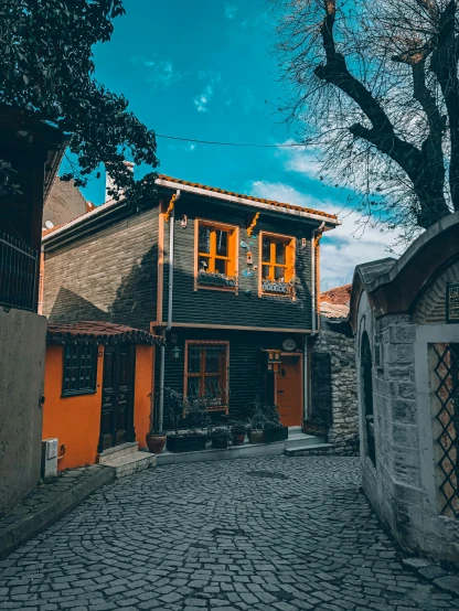 a cobblestone street with a house in the background, by Julia Pishtar, pexels contest winner, art nouveau, ayanamikodon and irakli nadar, black and orange colour palette, wooden house, turkey