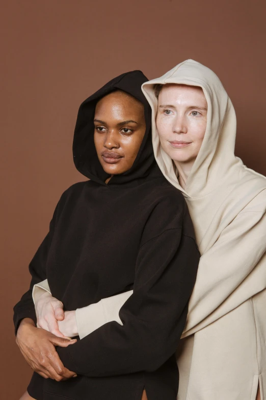 a couple of women standing next to each other, inspired by Vanessa Beecroft, trending on unsplash, renaissance, wearing hood, mixed race, with a white complexion, black and brown
