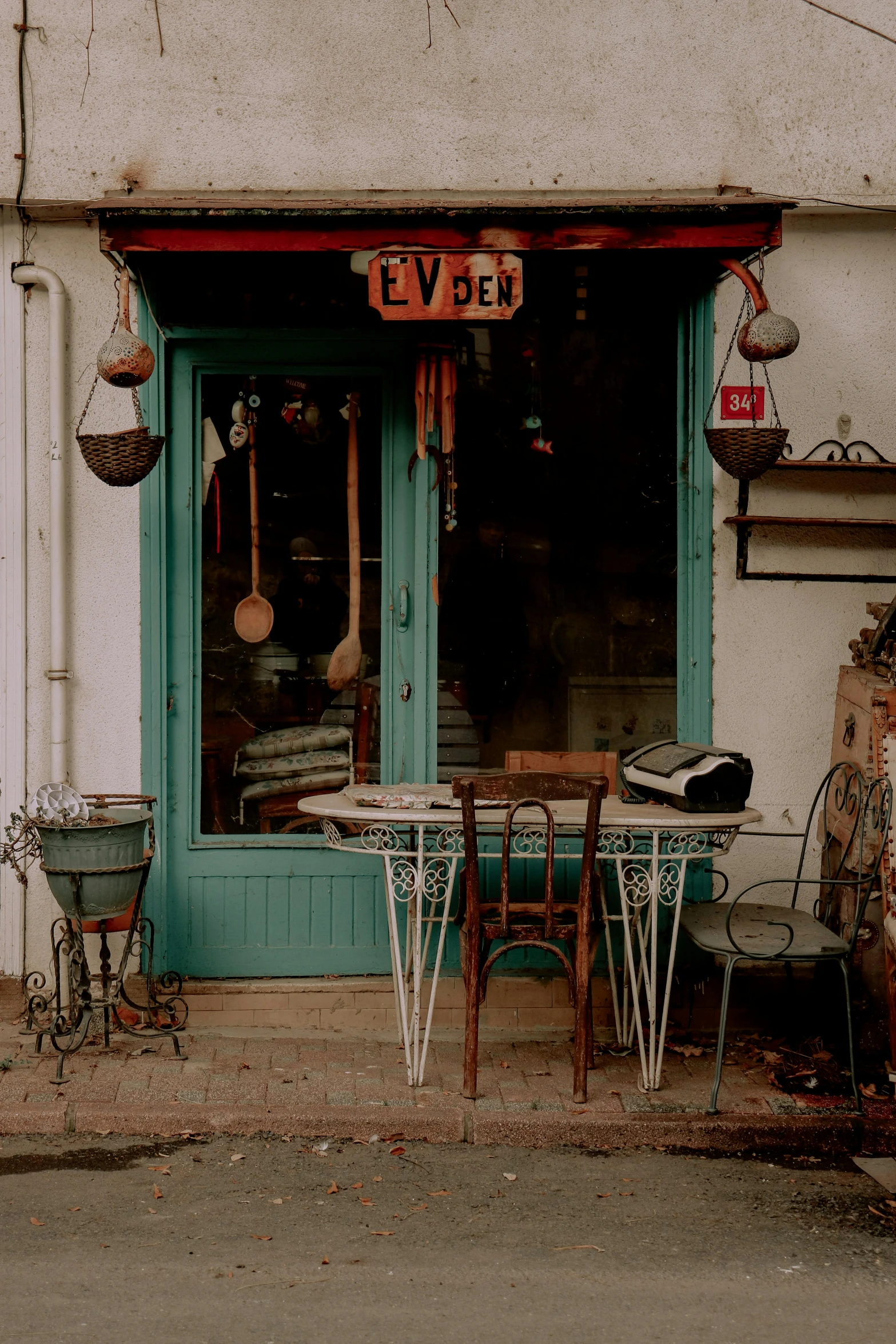 a motorcycle parked in front of a store, by Elsa Bleda, unsplash, art nouveau, tables and chairs, verdigris, quaint village, 1990's photo