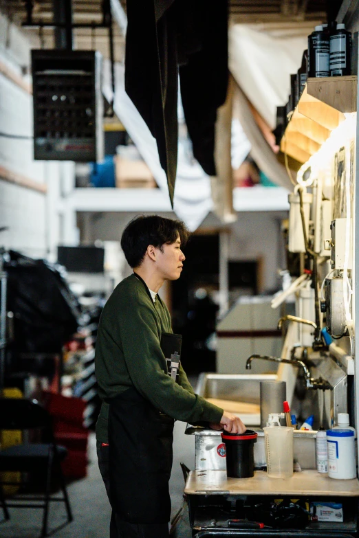 a man standing in a kitchen preparing food, a silk screen, unsplash, robot repair shop, asian man, working clothes, introduction factory photo