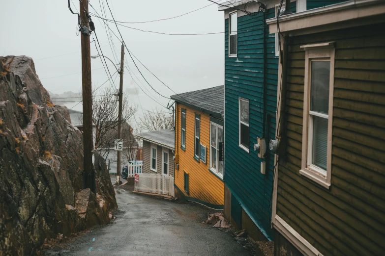 a couple of houses sitting on the side of a road, by Carey Morris, pexels contest winner, vibrant but dreary gold, small port village, street of teal stone, top of the hill