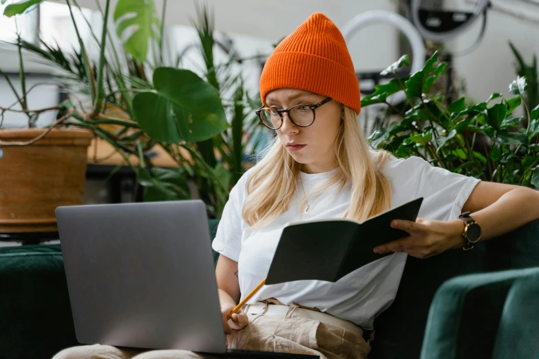 a woman sitting on a couch using a laptop, trending on pexels, renaissance, wearing a beanie, plants in glasses, avatar image, student