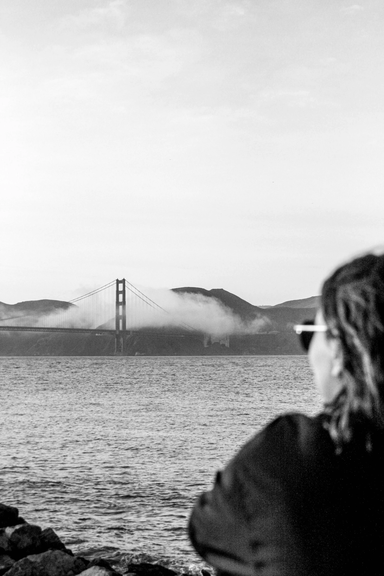 a woman taking a picture of the golden gate bridge, a black and white photo, by Dave Melvin, smoke on the water, ffffound, bjarke ingels, overexposed photograph