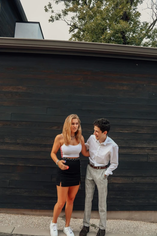 a man and a woman standing next to each other, an album cover, unsplash, preppy style, in front of a garage, white skirt and barechest, sydney hanson