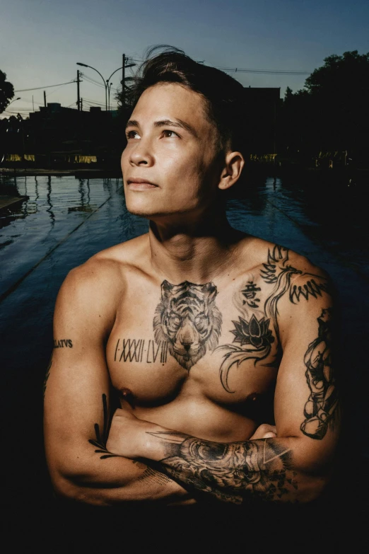 a man with tattoos standing in front of a body of water, inspired by Randy Vargas, an epic non - binary model, justin sun, profile image, swimming