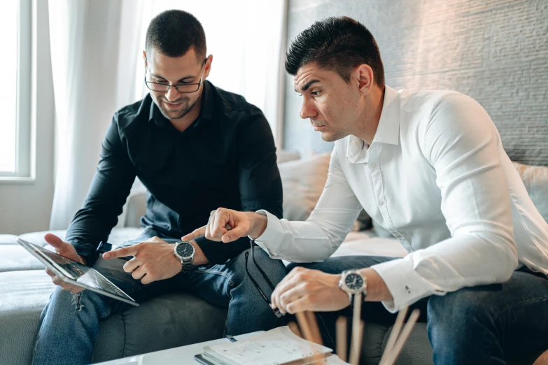 two men sitting on a couch looking at a tablet, by Adam Marczyński, pexels contest winner, working on a laptop at a desk, 9 9 designs, mc escher and ronny khalil, selling insurance