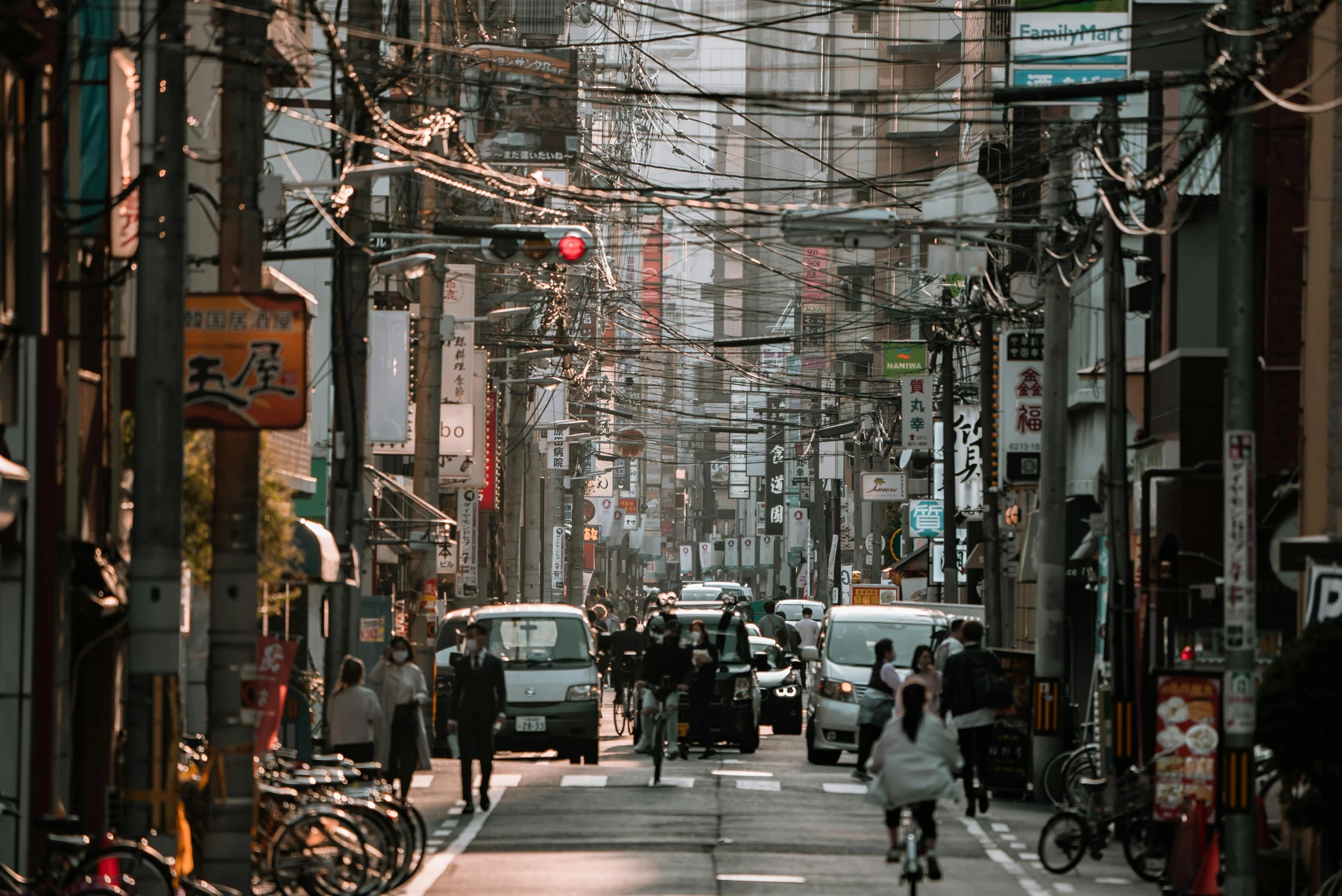 a group of people riding bikes down a street, pexels contest winner, ukiyo-e, machines and wires everywhere, photograph of the city street, brown, high resolution photo
