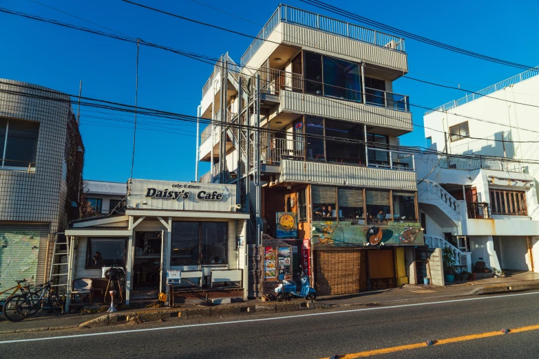 a tall white building sitting on the side of a road, a portrait, by Daniel Lieske, unsplash, shin hanga, japan shonan enoshima, diner caffee, rusty, 15081959 21121991 01012000 4k