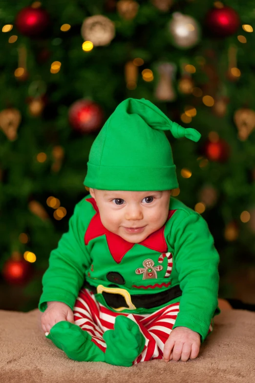 a baby sitting in front of a christmas tree, inspired by Ernest William Christmas, happening, a male elf, baggy clothing and hat, medium close up, green