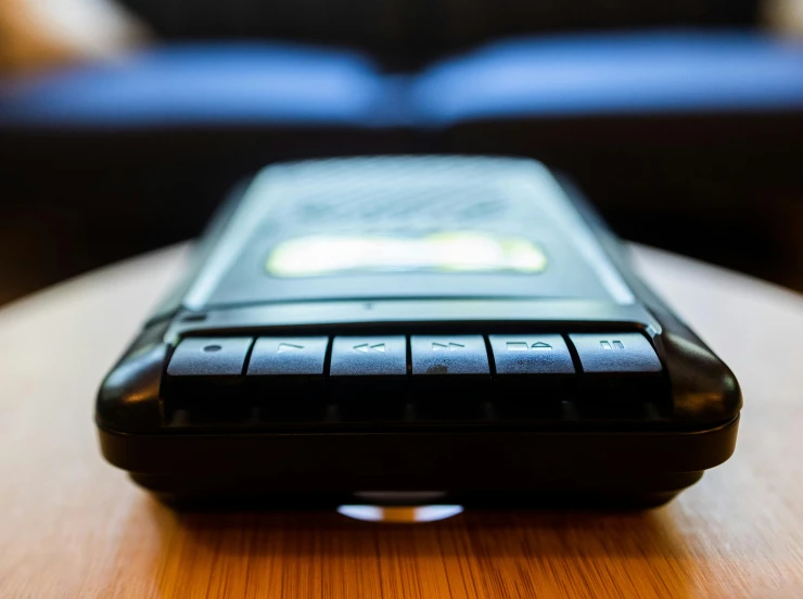 a cell phone sitting on top of a wooden table, psion, up-close, gorecore, radio