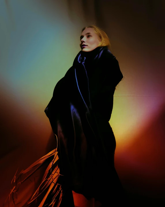 a woman standing in front of a colorful light, an album cover, cate blanchet, dressed in dark garment, showstudio, asher duran