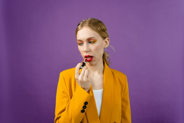 a woman is putting lipstick on her lips, by Julia Pishtar, trending on pexels, pop art, a purple suit jacket, ocher, commercial, sydney sweeney