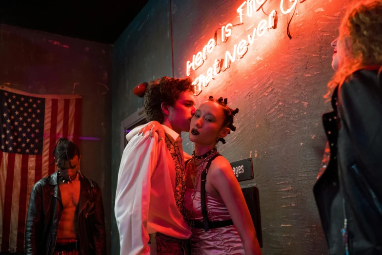 a man and a woman kissing in front of a neon sign, inspired by Nan Goldin, renaissance, in a cyberpunk themed room, lost boys, drag, premiere