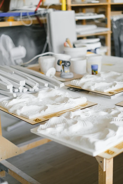 a table topped with lots of white stuff on top of a wooden table, a marble sculpture, arbeitsrat für kunst, 3 d print, white panels, professional product photo, in a workshop