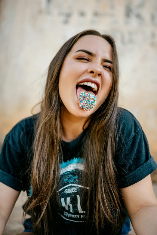 a girl sitting on the ground with a doughnut in her mouth, trending on unsplash, earing a shirt laughing, metal teeth, sugar sprinkled, patterned