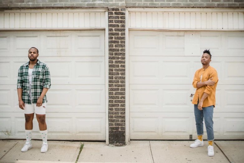 two men standing in front of a garage door, by Andrew Stevovich, pexels contest winner, diverse outfits, two women, teddy fresh, location [ chicago ( alley ) ]