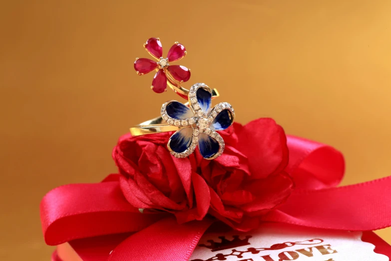 a ring sitting on top of a red ribbon, purple and red flowers, sapphire butterfly jewellery, gold jewellery, thumbnail