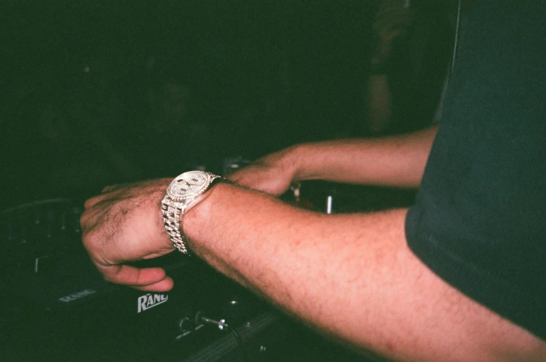 a close up of a person using a dj controller, by Pablo Rey, unsplash, holding gold watch, college party, grainy film photo, low - lighting