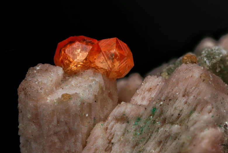 a couple of orange stones sitting on top of a rock, a macro photograph, unsplash contest winner, synthetism, red emerald, elbaite, 2022 photograph, micro detail 4k