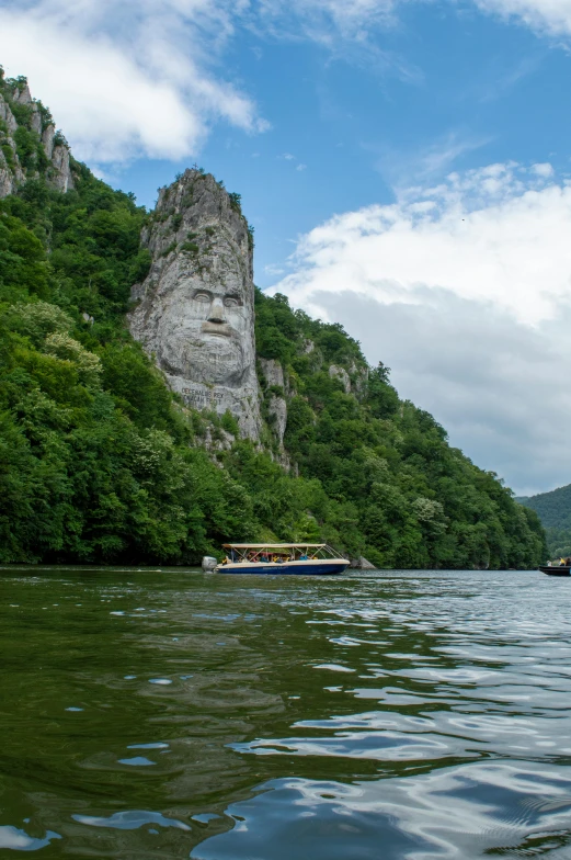 a boat traveling down a river next to a mountain, danube school, beautiful sculptured face, powerful chin, scowling