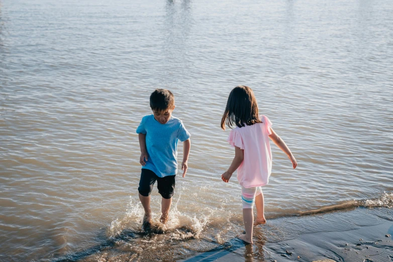 a couple of kids that are standing in the water, pexels contest winner, incoherents, 15081959 21121991 01012000 4k, walking to the right, te pae, at the waterside