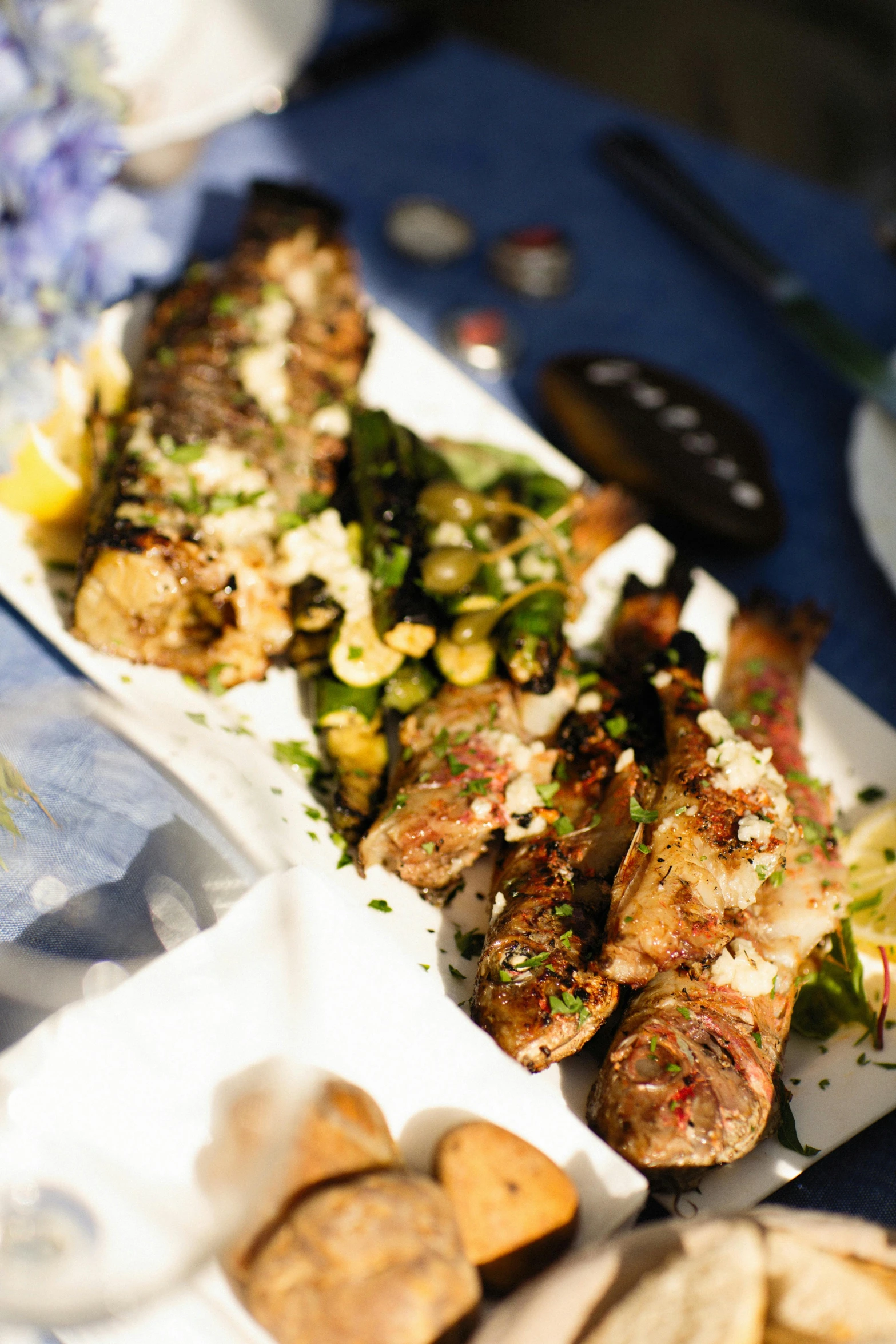 a close up of a plate of food on a table, fishes, barbecue, profile image, greek ameera al taweel