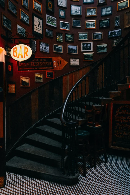 a room with a spiral staircase and pictures on the wall, pexels contest winner, local bar, stairway, gif, low quality photo