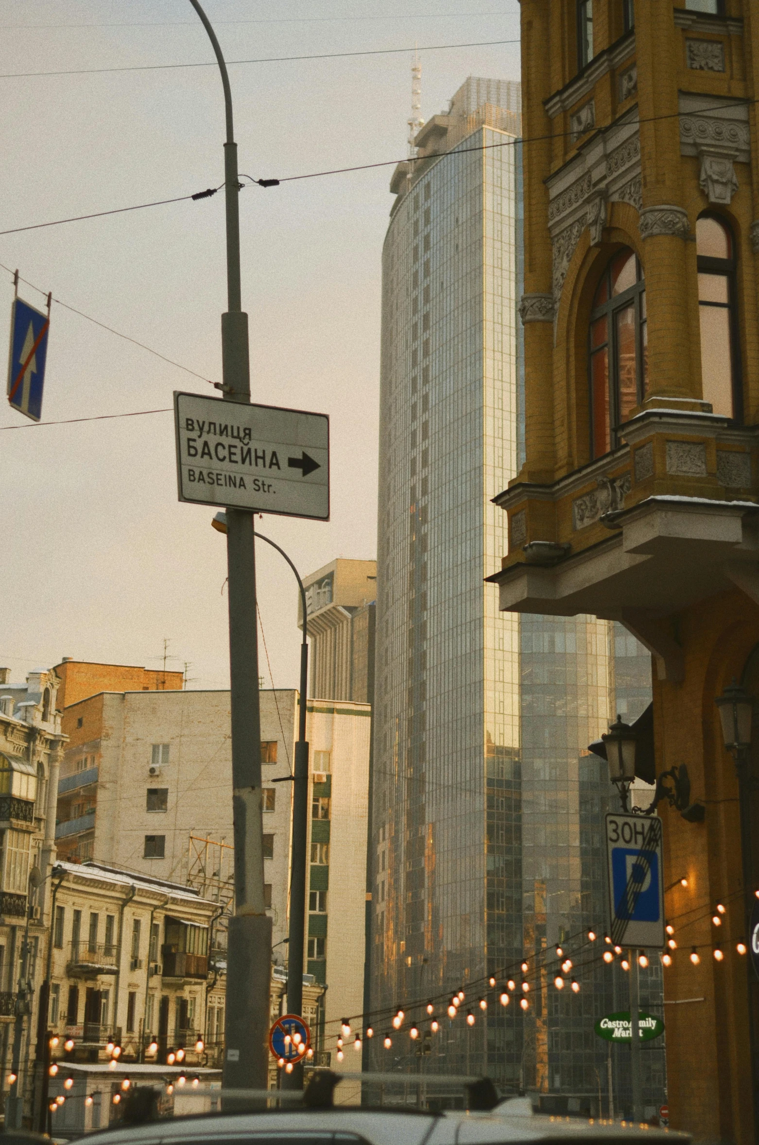 a city street filled with lots of traffic next to tall buildings, socialist realism, street signs, low quality photo, romanian heritage, evening light