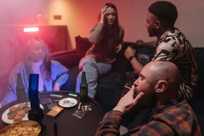 a group of people sitting around a table with food, smoking a blunt, sitting in a lounge, bisexual lighting, playing games