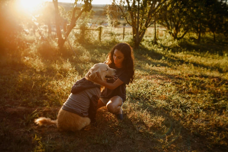 a woman sitting in the grass with a dog, by Emma Andijewska, pexels, soft golden light, aussie, embrace, instagram post