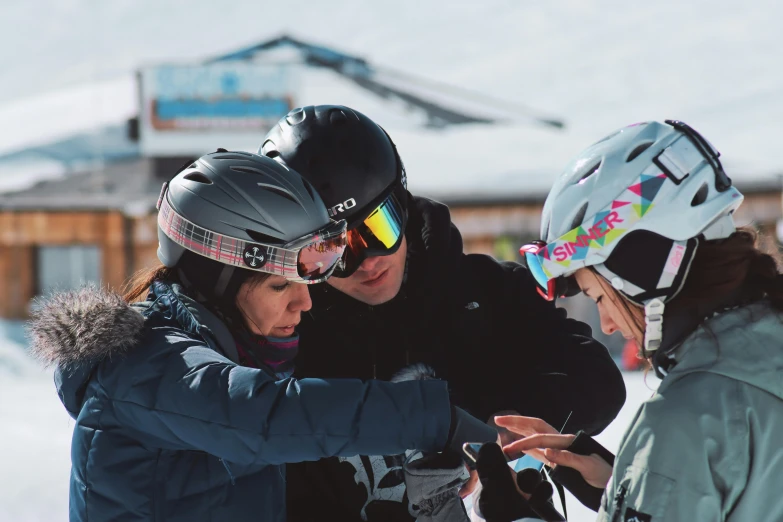 a group of people standing on top of a snow covered slope, checking her phone, ski masks, avatar image, teaching