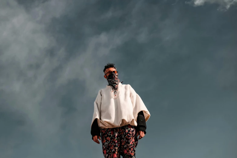 a man riding a snowboard down a snow covered slope, an album cover, trending on pexels, afrofuturism, wearing desert poncho, standing on a rooftop, white man with black fabric mask, portrait mode photo