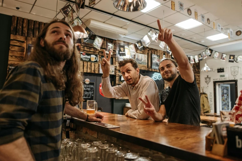 a group of men standing next to each other at a bar, pexels contest winner, private press, giving the middle finger, aussie baristas, beers on the table, artists