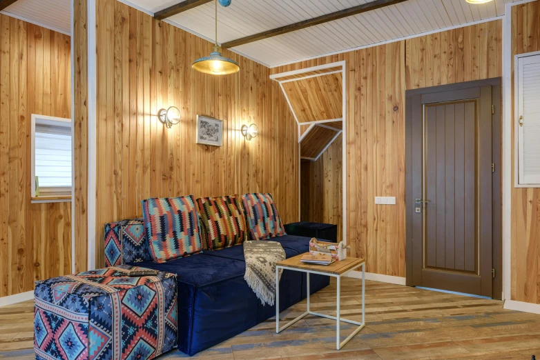 a living room with wood paneling and a blue couch, by Julia Pishtar, unsplash, neo kyiv, wooden cottage, 3 doors, paisley