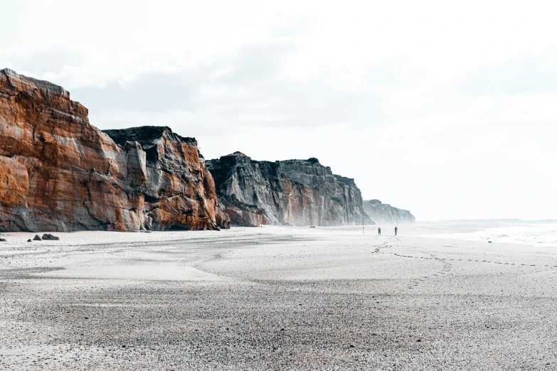 a group of people standing on top of a sandy beach, by Andries Stock, pexels contest winner, minimalism, coastal cliffs, the normandy landings, rocky cliffs, viewed from a distance