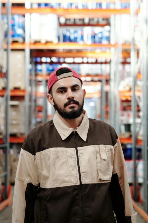 a man standing in a warehouse looking at the camera, inspired by Eddie Mendoza, wearing a red backwards cap, enes dirig, polychromatic, profile image