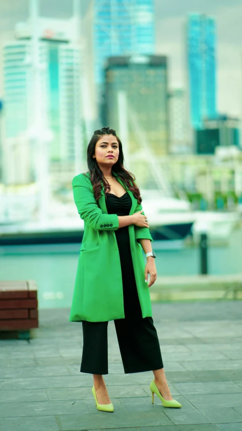 a woman standing in front of a body of water, an album cover, pexels, hurufiyya, wearing green jacket, movie still 8 k, street pic, aishwarya rai