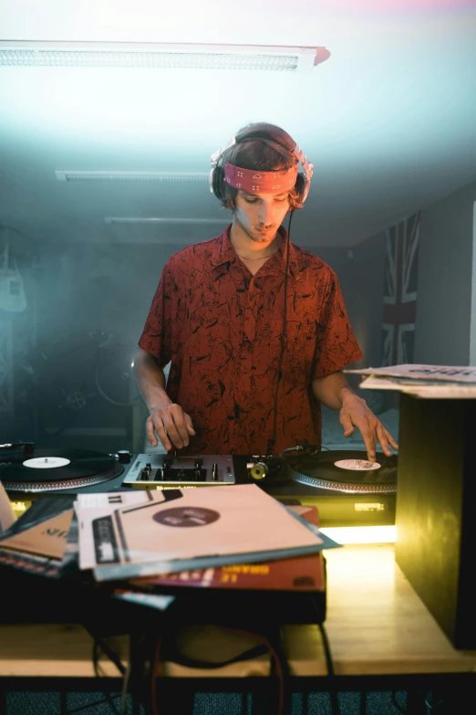 a man that is standing in front of a table, an album cover, unsplash, dj at a party, in his basement studio, performing a music video, julian ope