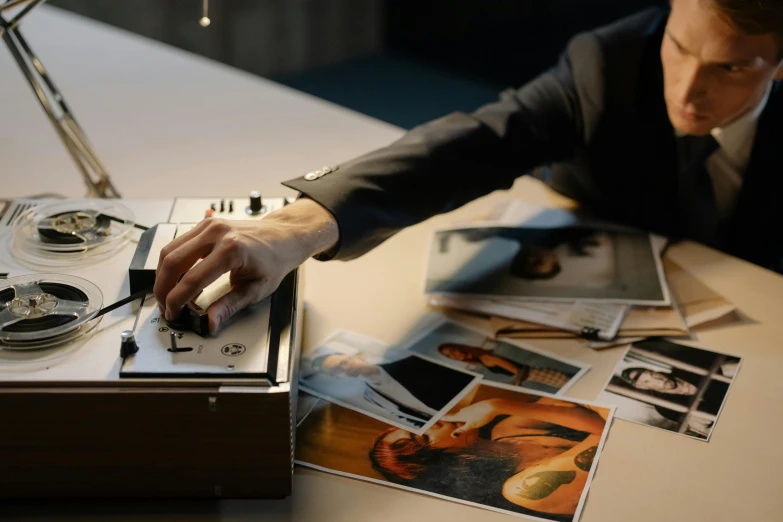 a man in a suit holding a tape recorder, an album cover, unsplash, hyperrealism, on a desk, hasselblad photo, animation, 4 k film still