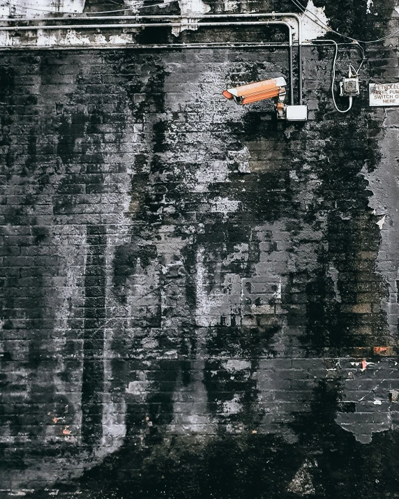 an orange umbrella sitting on top of a brick wall, inspired by Elsa Bleda, pexels contest winner, graffiti, buildings covered in black tar, security camera photo, background image, dripping black and grey paint