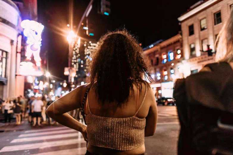 a woman standing on a city street at night, happening, focus her back, montreal, profile image, fan favorite