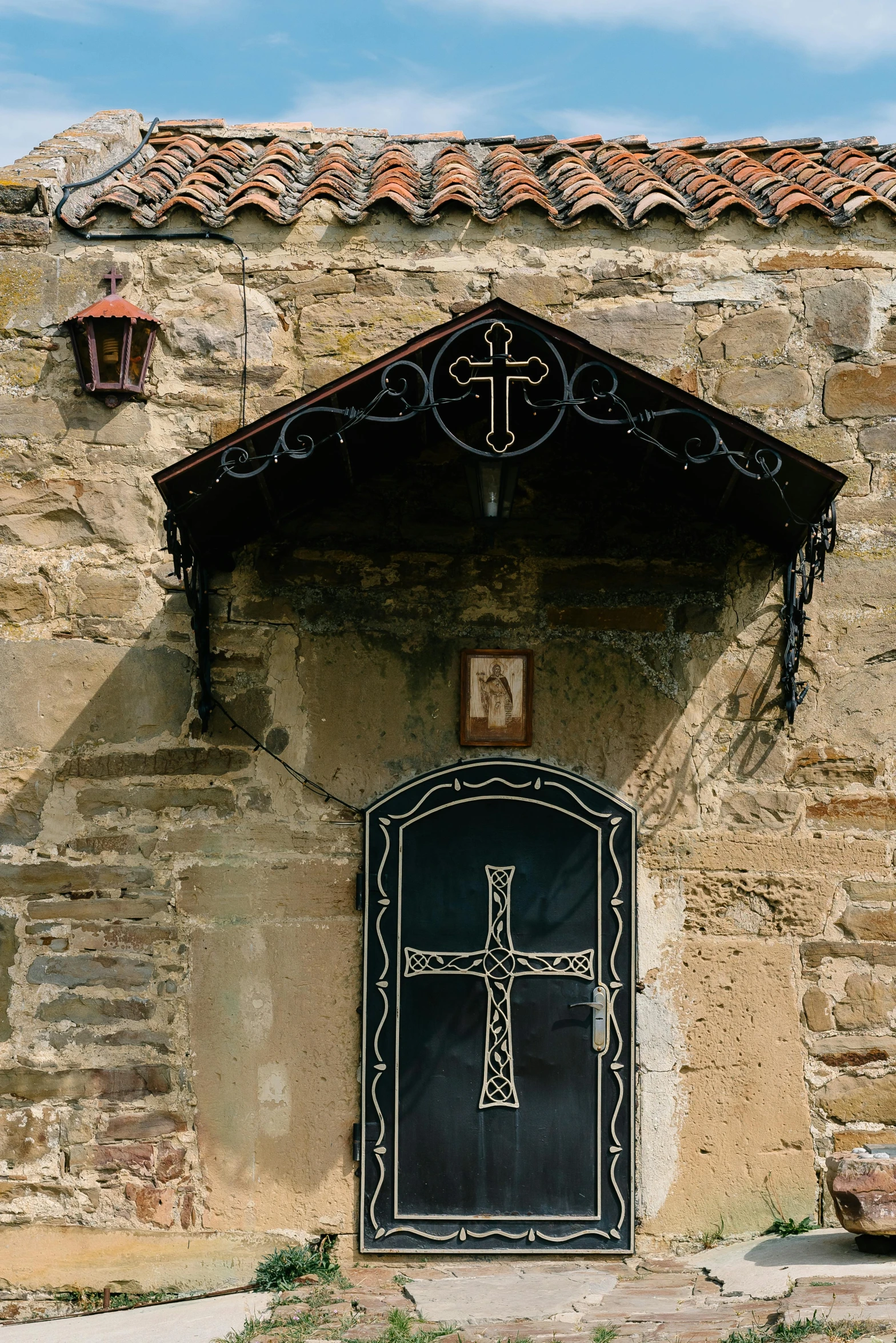 a stone building with a black door and a cross on it, inspired by Károly Markó the Elder, romanesque, orthodox icons, prague, crucifixion, quaint