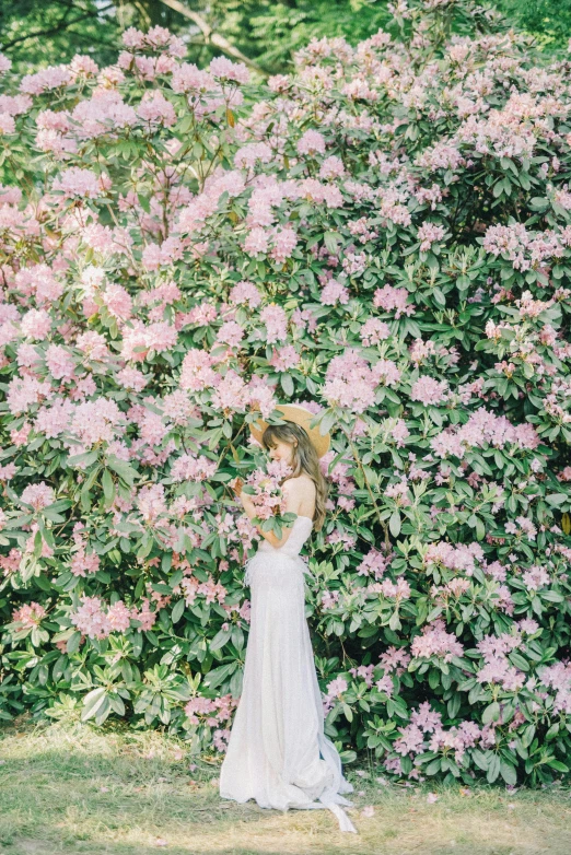 a woman standing in front of a bush of flowers, inspired by Oleg Oprisco, unsplash contest winner, wedding, in style of cecil beaton, with a long, hoang long ly