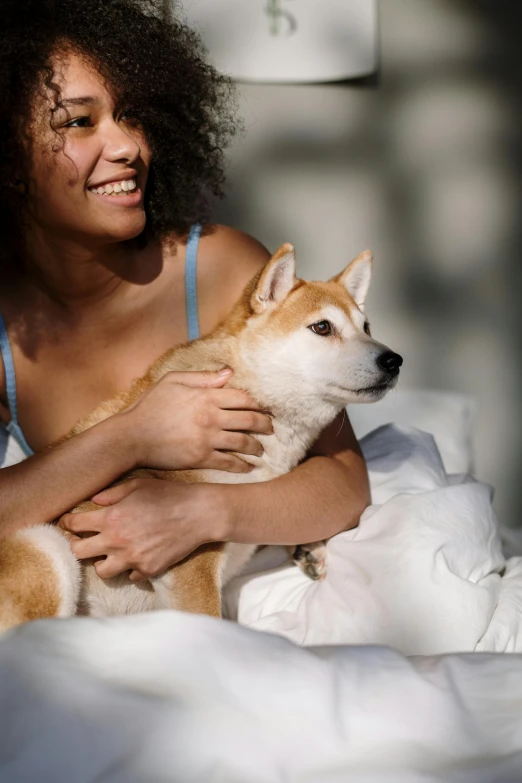 a woman sitting on a bed holding a dog, a stock photo, trending on unsplash, renaissance, shiba inu, lesbian embrace, zoomed in, kano)