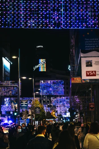 a crowd of people walking down a street at night, digital billboard in the middle, sri lanka, decorations, madrid